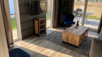 A modern living room with a flat-screen TV, a wooden coffee table, a blue chair, and a sofa.