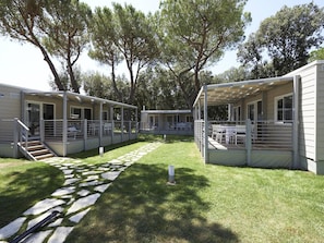 A row of modern, single-story cabins with outdoor seating areas, connected by a stone pathway. - Serene Stay by the Shore (Cellole)