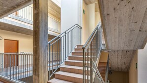 Ein mehrgeschossiges Interieur mit Treppe, Metallgeländern und Fliesenböden.