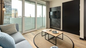 Een moderne woonkamer met een bank, een salontafel en een televisie bevestigd aan een marmeren muur.