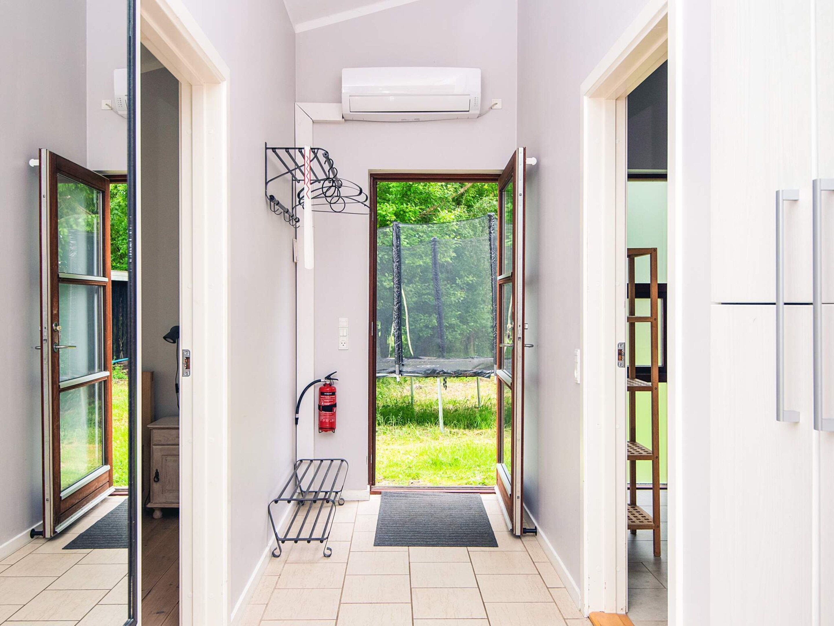 A hallway with a fire extinguisher, a metal rack, and a door leading to a trampoline in a green outdoor area.