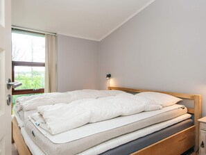 Une chambre à coucher avec un lit, une table de chevet et une fenêtre avec des rideaux.