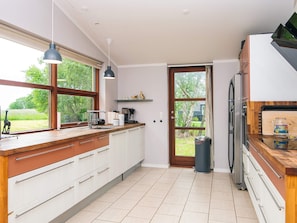 A modern kitchen with a large window, a built-in oven, and a trash bin. - Holiday Home in Knebel (Knebel)
