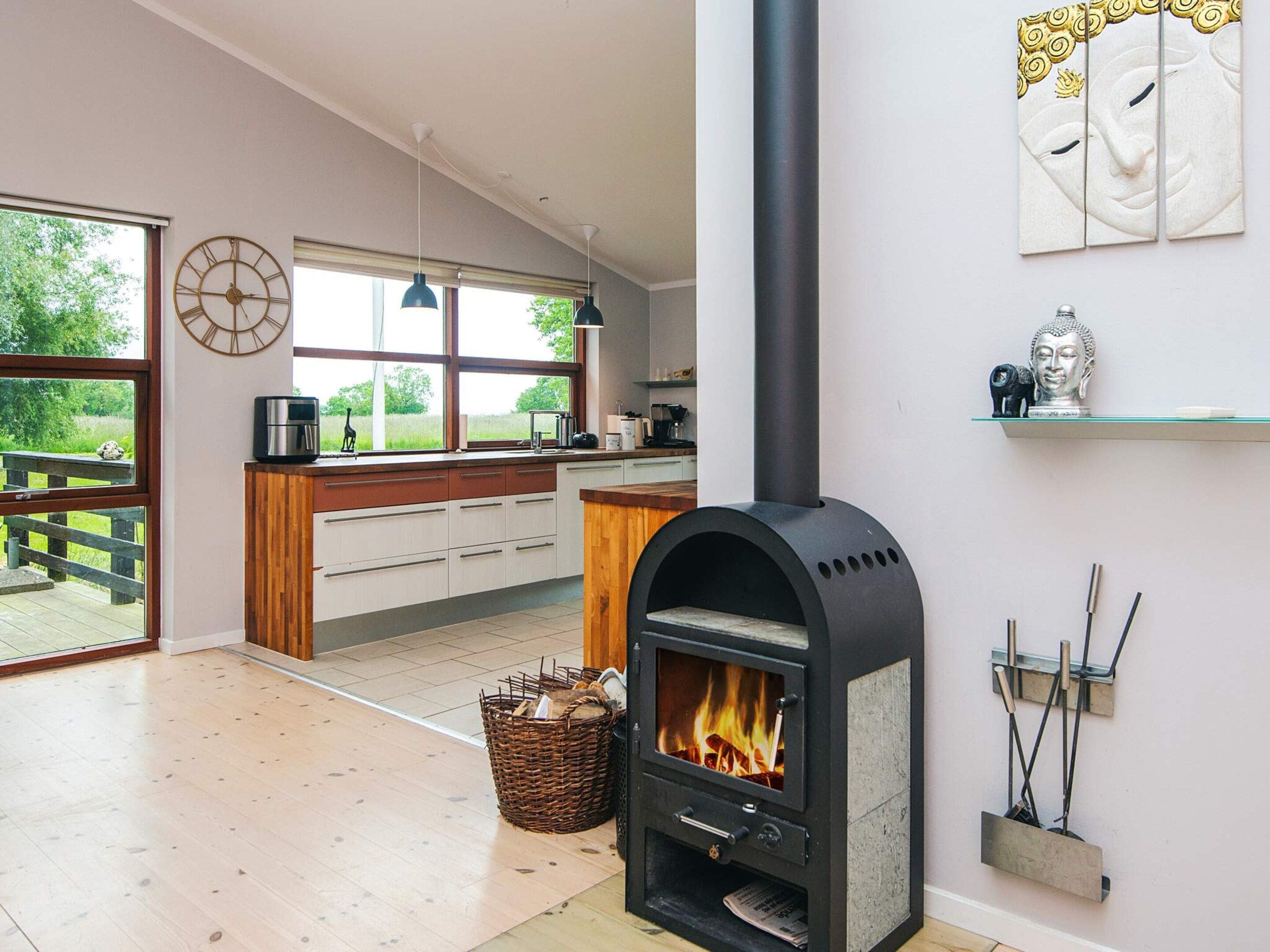 A modern kitchen with a wood-burning stove, a dining area with a view, and a large window.