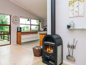 A modern kitchen with a wood-burning stove, a dining area with a view, and a large window.