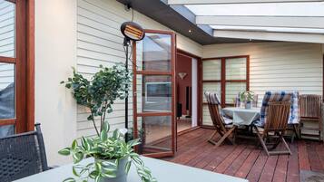 An outdoor patio with a table and chairs, a potted plant, and a heater.