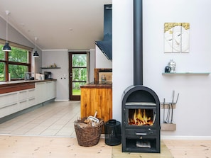 A modern kitchen with a wood-burning stove, a large window, and a view of the outdoors.