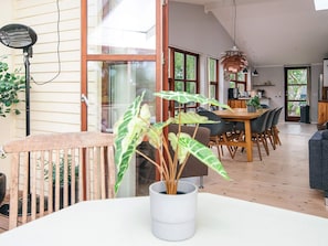 A spacious dining area with a large table and chairs, a kitchen in the background, and a view of the outdoors through large windows. - Holiday Home in Knebel (Knebel)