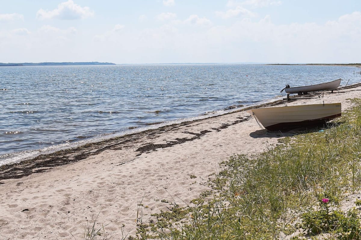 A beach with boats and seaweed on the shore.