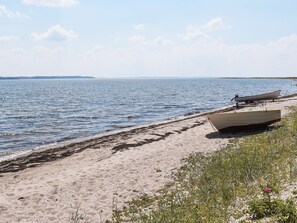 A beach with boats and seaweed on the shore.