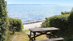 Ett picknickbord i trä med bänkar, placerat vid en strand.