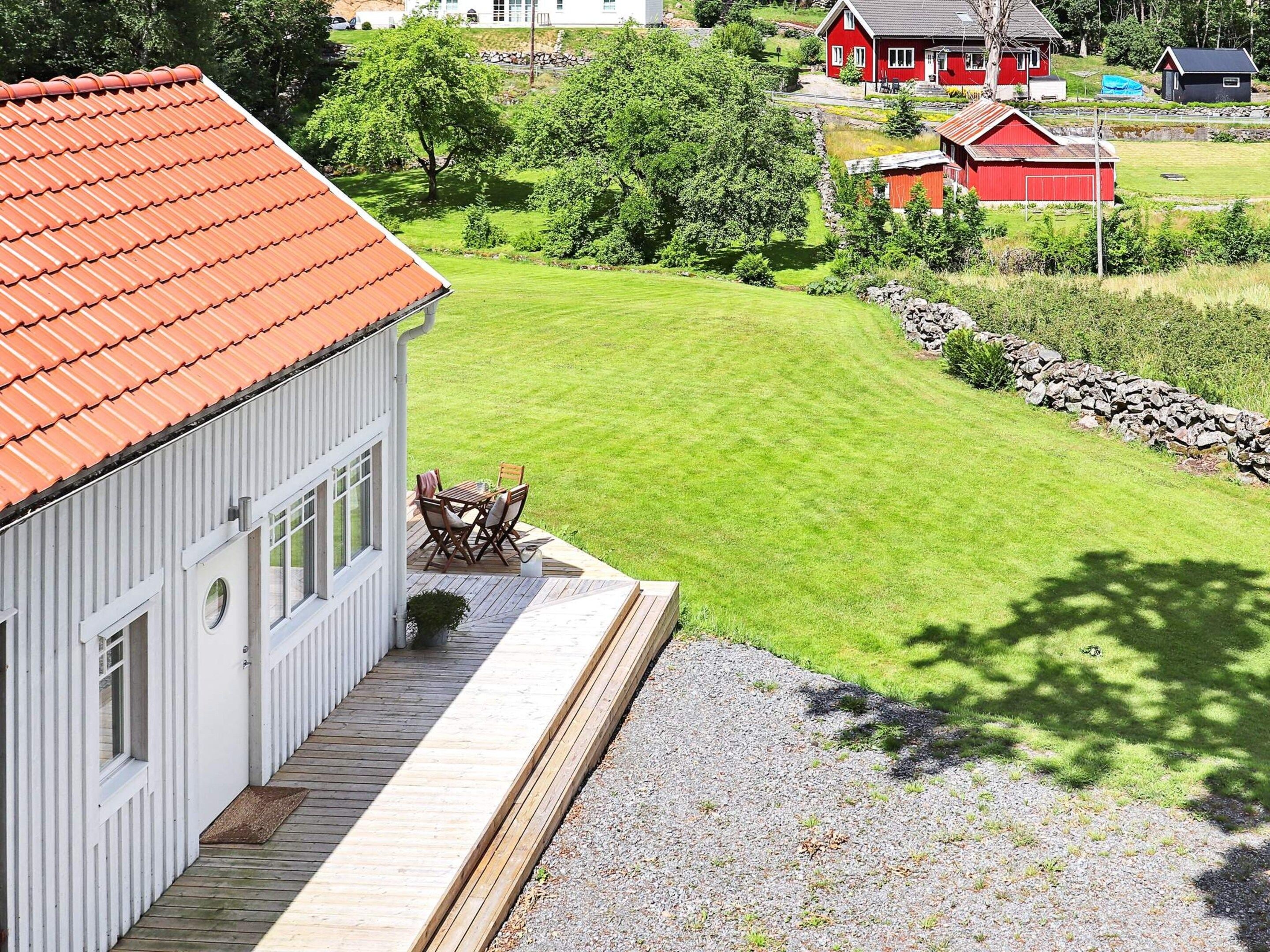 A house with a red roof, a deck, and a lawn.