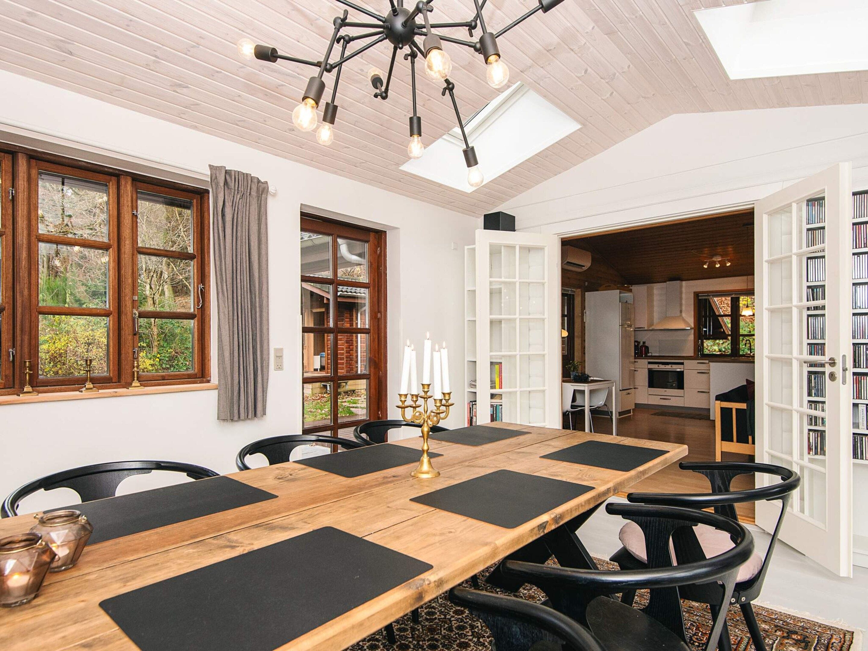 A dining area with a wooden table, black chairs, and a chandelier.