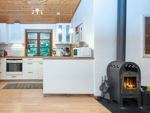 Et moderne køkken med hvide skabe, indbygget ovn, mikroovn og brændeovn.
