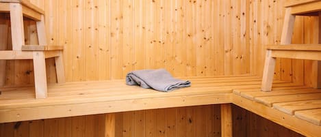 Un sauna avec des bancs en bois et un banc muni d’une serviette.