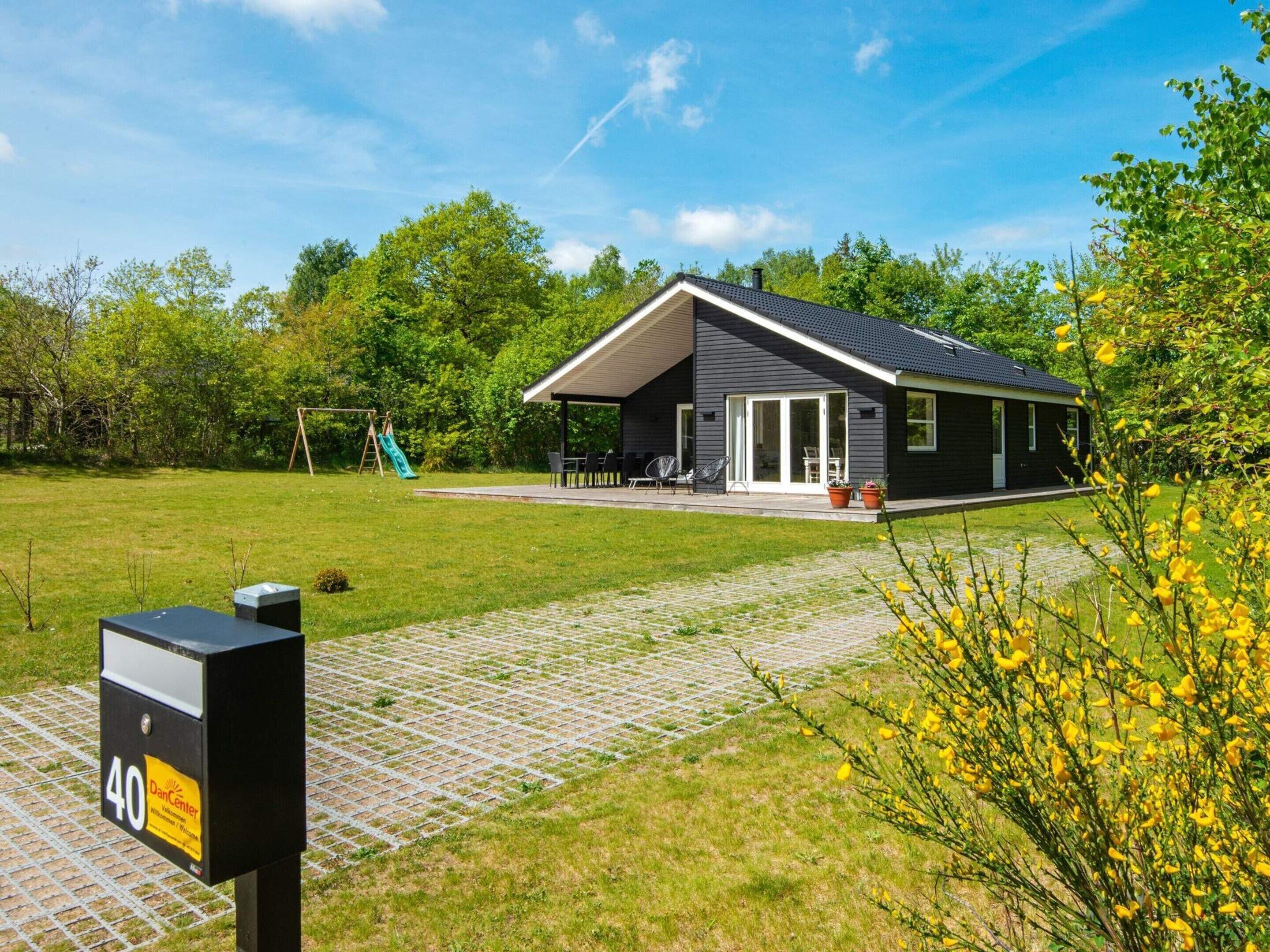 Une maison moderne dotée d’un patio couvert, d’une balançoire et d’une allée pavée.