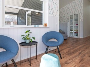 A room with two blue chairs, a small table with a plant, a window with a view, and a cabinet with glass doors. - Holiday Home in Silkeborg (Silkeborg)