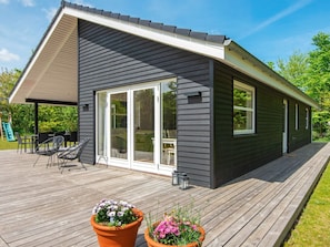 Una casa moderna con terraza, puertas corredizas amplias y mobiliario exterior.