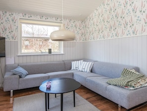 Una habitación con un sofá gris, una mesa redonda negra y una lámpara colgante.