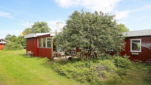 A red wooden house with a small attached shed, a lawn, and a large tree in front. - 6 Person Holiday Home in Gorlev (Gørlev)