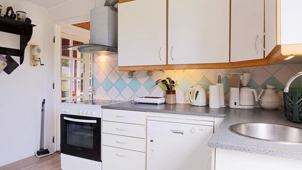 A compact kitchen with white cabinets, a built-in oven, a dishwasher, and a coffee maker. - 6 Person Holiday Home in Gorlev (Gørlev)