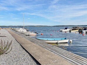 A dock with boats moored along it, a pebble beach, and calm water. - 7 Person Holiday Home in Hakenaset (Hakenäset)