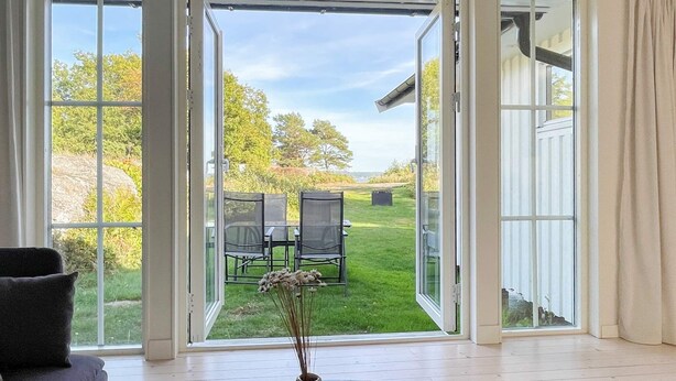 A room with a large sliding glass door leading to an outdoor patio with a table and chairs. - 7 Person Holiday Home in Hakenaset (Hakenäset)