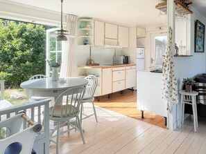 A kitchen with a dining area, wooden flooring, and a view of greenery outside. - 7 Person Holiday Home in Hakenaset (Hakenäset)