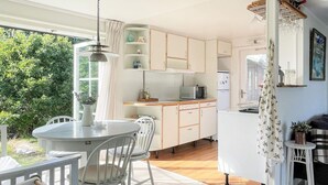 A kitchen with wooden cabinets, a white refrigerator, and a dining area with a round table and chairs. - 7 Person Holiday Home in Hakenaset (Hakenäset)