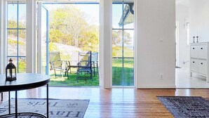 A spacious room with a large sliding glass door leading to a patio area. There is a round table with a lantern on it, and a rug with text on the floor. - 7 Person Holiday Home in Hakenaset (Hakenäset)