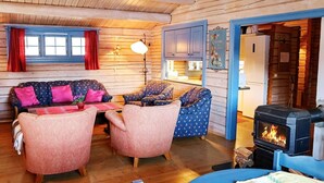 Een gezellig cabin interieur met houten wanden, een open haard, een zithoek en een eettafel.