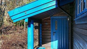 Een houten hut met een blauwe deur en een veranda.