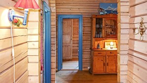 Een houten gang met een blauwe deur, een kast met glaswerk, en een rode lamp.