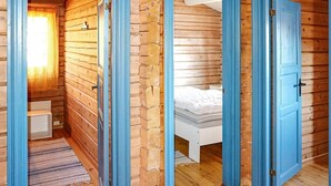 Een houten blokhut met een slaapkamer, badkamer en een klein zithoekje.