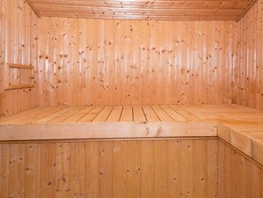 A wooden sauna room with a bench and a door.