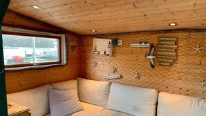 A cozy cabin interior with a wooden ceiling, a cushioned bench, and a wall-mounted sign with rules. - 6 Person Holiday Home in Bomlo (Bomlo)