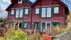 A two-story red wooden house with green window frames and white trim. - 6 Person Holiday Home in Bomlo (Bomlo)