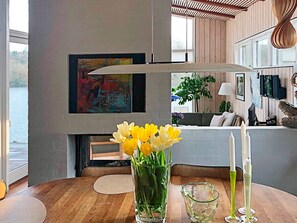 Un interior moderno con una mesa de madera, un jarrón de flores amarillas y un cuadro en la pared.