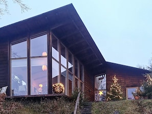 A modern wooden building with large windows and a sloped roof.