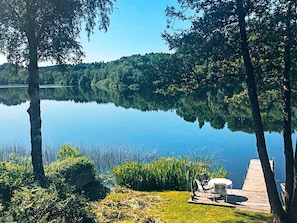 A serene lakeside setting with a wooden dock, a grassy area, and a bench.