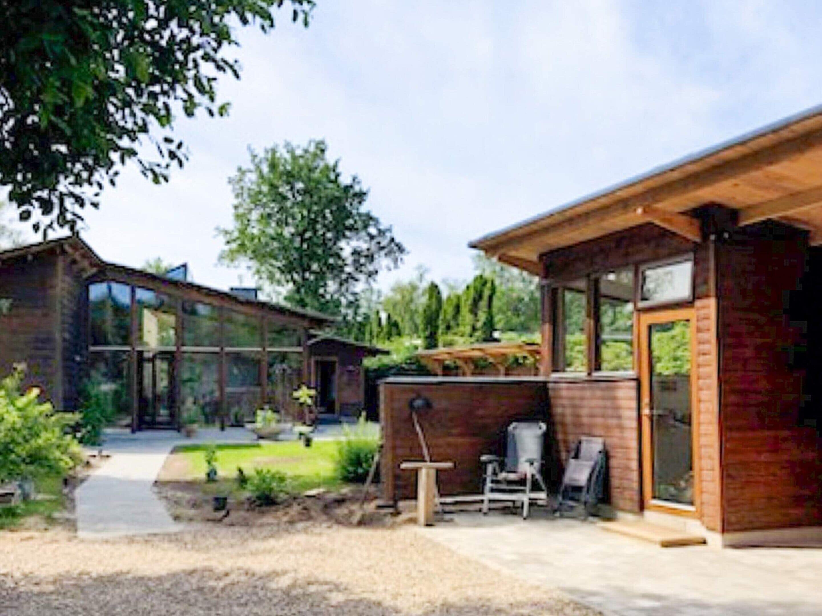 A modern house with a large glass window, a wooden deck, and a brick exterior.