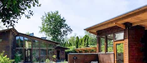 A modern house with a large glass window, a wooden deck, and a brick exterior.