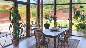 A sunlit room with a glass table, wicker chairs, and potted plants. - 5 Star Holiday Home in Bryrup (Bryrup)