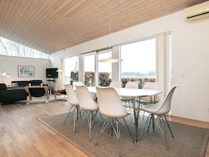 A modern living room with a dining area, large windows, and a view of the outdoors. - Holiday Home in Bogense (Bogense)