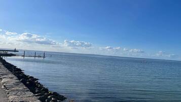 A calm sea with a stone breakwater and a pier extending into the water.