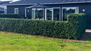A modern building with a dark exterior, large windows, and a well-maintained hedge in front. - Holiday Home in Bogense (Bogense)
