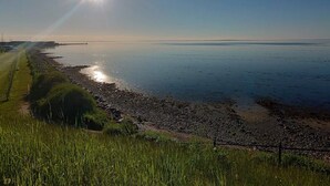 A coastal landscape with a clear sky, a sunlit horizon, and a grassy area with a fence. - Holiday Home in Bogense (Bogense)