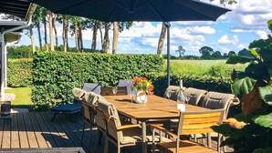 An outdoor dining area with a wooden table, chairs, and an umbrella. - Holiday Home in Bogense (Bogense)