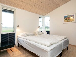 A bedroom with a bed, two bedside lamps, a window, and a painting on the wall. - Holiday Home in Bogense (Bogense)