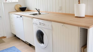 A compact kitchen with a built-in washing machine, a sink, and a wooden countertop. - 4 Person Holiday Home in Blokhus (Blokhus)
